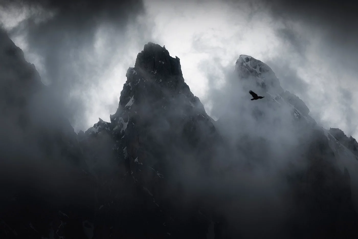 Aiguilles rocheuses surgissant de la brume avec un oiseau en vol